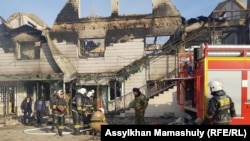 Сотрудники департамента по чрезвычайным ситуациям рядом со сгоревшим зданием в Масанчи.