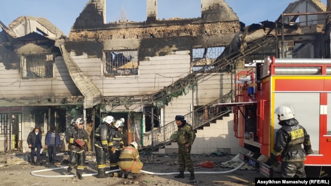 Сотрудники департамента по чрезвычайным ситуациям рядом со сгоревшим зданием в Масанчи.