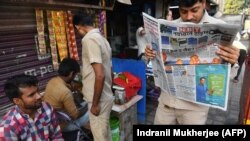 An auto-rickshaw driver reads a newspaper with front-page reports on the Indian air strikes against purported militant camps in Pakistan's territory, in Mumbai, on February 27.