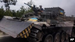 Ukrainian soldiers ride a tank on a road in Stupochky in Ukraine's eastern Donetsk region.