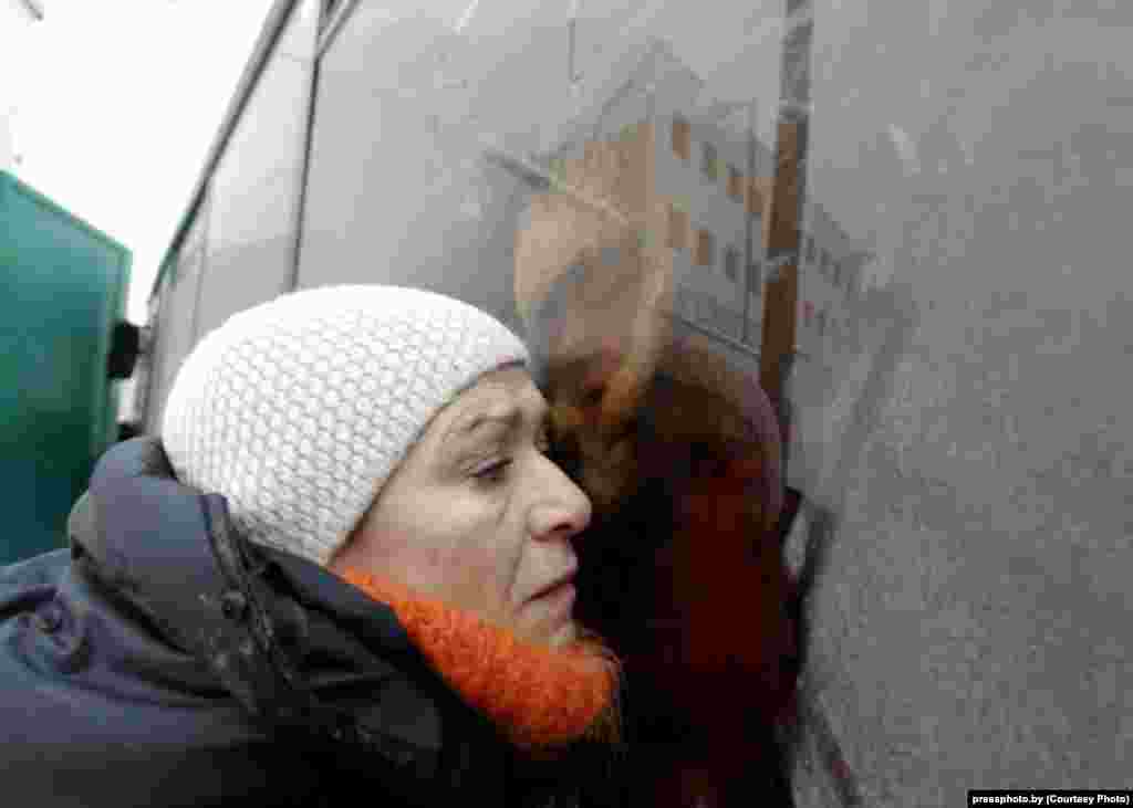 A woman tries to hear what her relative in a police bus is saying following an antigovernment protest in Minsk. Photo by Vasil Fyadosenka