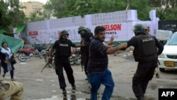 Pakistani policemen arrest an activist of the Muttahida Qaumi Movement (MQM) political party during a clash in Karachi on August 22.