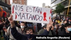 Un manifestant ține un semn pe care scrie „Ne omoară” în timpul unui protest în Bogota, Columbia, 4 mai 2021