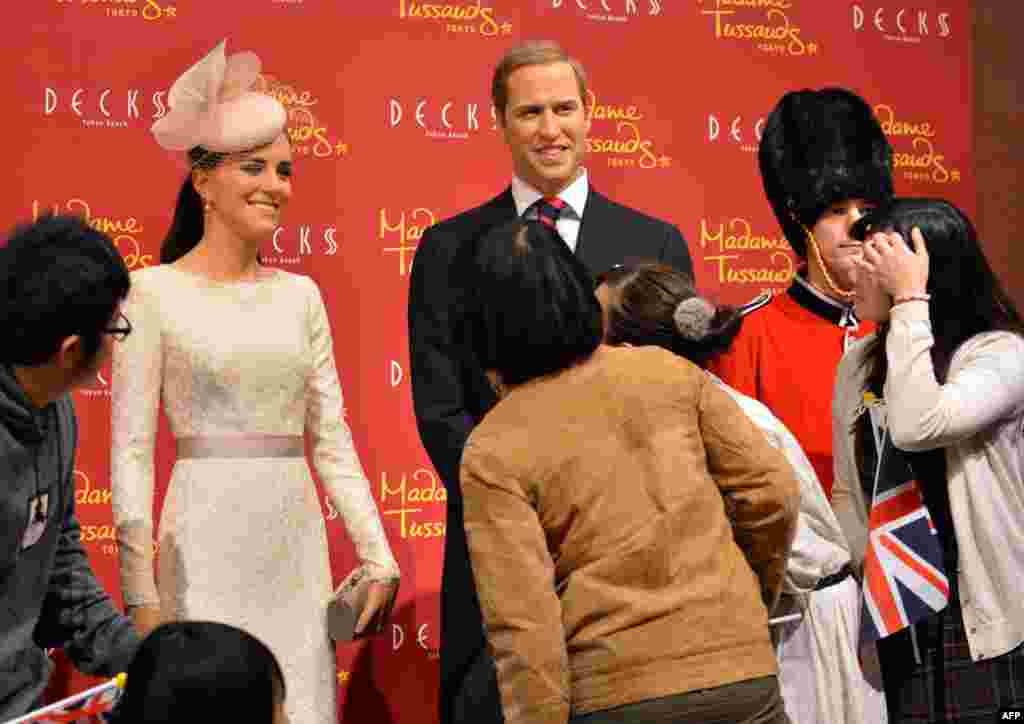 People inspect wax figures of Britain&#39;s Catherine, Duchess of Cambridge (left), and Prince William at a press preview in Tokyo. The Madame Tussauds museum in Tokyo will be reopened in March 2013 with more than 60 waxworks expected to be displayed. (AFP/Yoshikazu Tsuno)