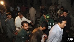 Rescuers and security personnel remove an injured victim at the site of the Karachi bombing.