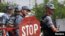 Police officers stand at a checkpoint near the border with Ingushetia, where a suicide bomber blew himself up near the village of Chermen, on August 17.