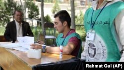 FILE: Employees of the Independent Election Commission registers a voter at a registration center in Kabul in June.