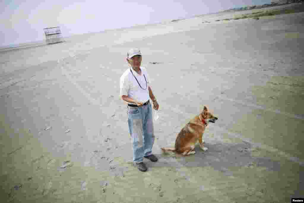 Local resident Takeshi Takaki, 71, and his dog stroll on the beach about 40 kilometers (25 miles) south of the nuclear power plant. The city of Iwaki closed its beach to the public during the summer season for the first time since the March 2011 earthquake that damaged the nuclear plant.