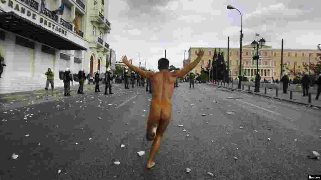 A naked protester runs past the parliament in Syntagma Square in Athens during a violent protest against a&nbsp; visit by German Chancellor Angela Merkel on October 9. Tens of thousands of demonstrators defied a ban on protests to voice their displeasure with the German leader, who many blame for forcing painful austerity measures on Greece. (Reuters/John Kolesidis)