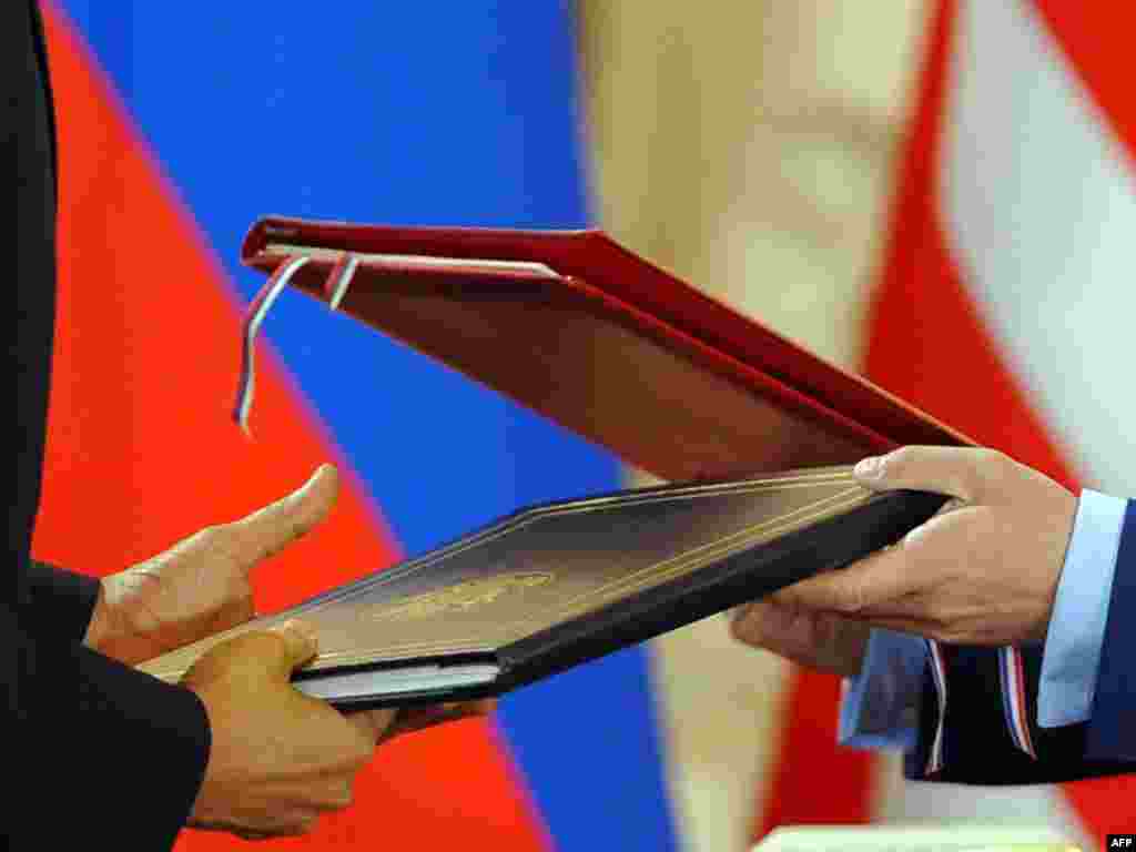 U.S. President Barack Obama and his Russian counterpart Dmitry Medvedev hand off their newly signed arms treaty. - At their summit in Prague on April 8, the two leaders signed a landmark deal on reducing their countries' nuclear arsenals after months of tough negotiations. Photo by Jewel Samad for AFP