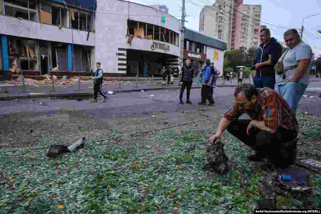 Un bărbat inspectează o bucată de motor după atacurile rusești cu drone de la Kiev, din noaptea de 20 spre 21 iulie. În fundal se vede o intrare în stația de metrou Lukianivska.