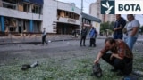 Një burrë inspekton një pjesë motori pas sulmeve ajrore ruse me dronë gjatë natës në Kiev, më 20-21 korrik. Në sfond shihet hyrja e stacionit të metrosë Lukyanivska.