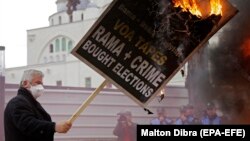 A supporter of the opposition holds a burning banner during a protest outside the Albanian parliament in Tirana on March 5.