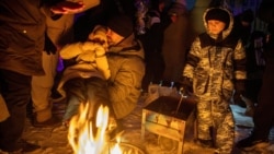 People warm themselves at a bonfire in a Kyiv neighborhood left without electricity after a Russian strike in January. 