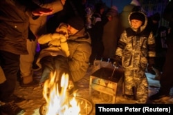 Люди греются у костра в Киеве, Украина, 24 января 2026 года