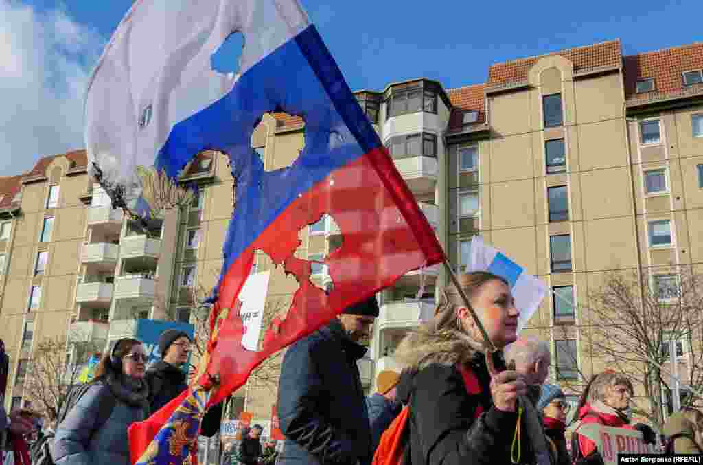 A protester with a burnt Russian flag during a demonstration on March 1 in Berlin called by Russian opposition leaders opposing the Kremlin's invasion of Ukraine.Photo by Anton Sergienko/RFE/RL's Russian Service.