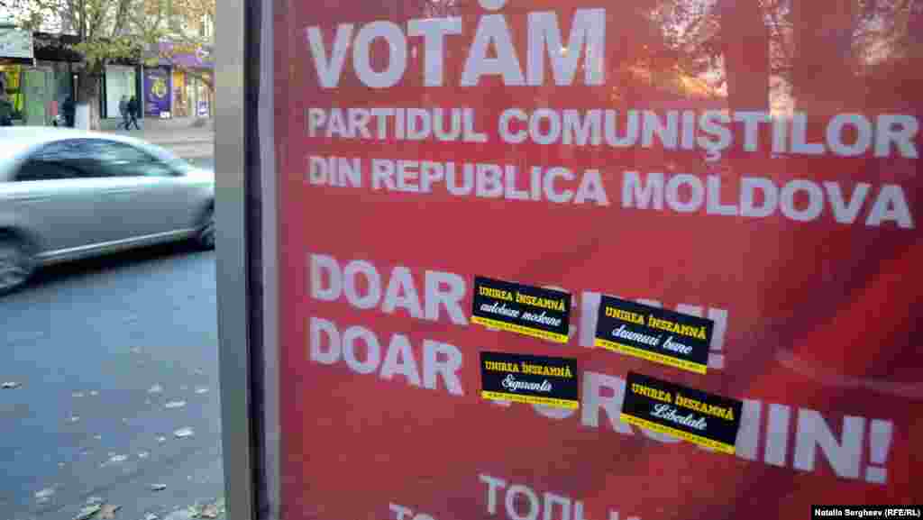 Abţibilduri &bdquo;Unirea Înseamnă&rdquo; lipite pe un panou cu publicitatea Partidului Comuniştilor din Republica Moldova. 