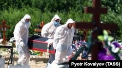 Cemetery workers wearing personal protective equipment bury a COVID-19 victim at a graveyard on the outskirts of St. Petersburg, Russia.