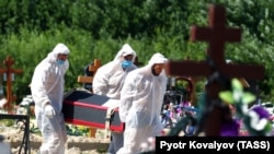Сотрудники ритуальной службы в защитных костюмах хоронят погибшего от коронавируса человека. Санкт-Петербург, 25 июня 2021 года.