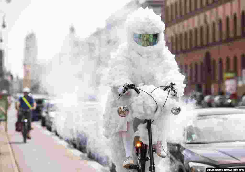 Artist Martin Nothhelfer rides as the Cloud Cyclist (Wolken Radler) at the Geschwister-Scholl-Platz in Munich, Germany. Nothhelfer wants to show with his performance where there is good air and bad air in Munich. His bicycle blows out soap bubbles when the air is clean, but in bad air it smokes. (EPA-EFE/Lukas Barth-Tuttas)