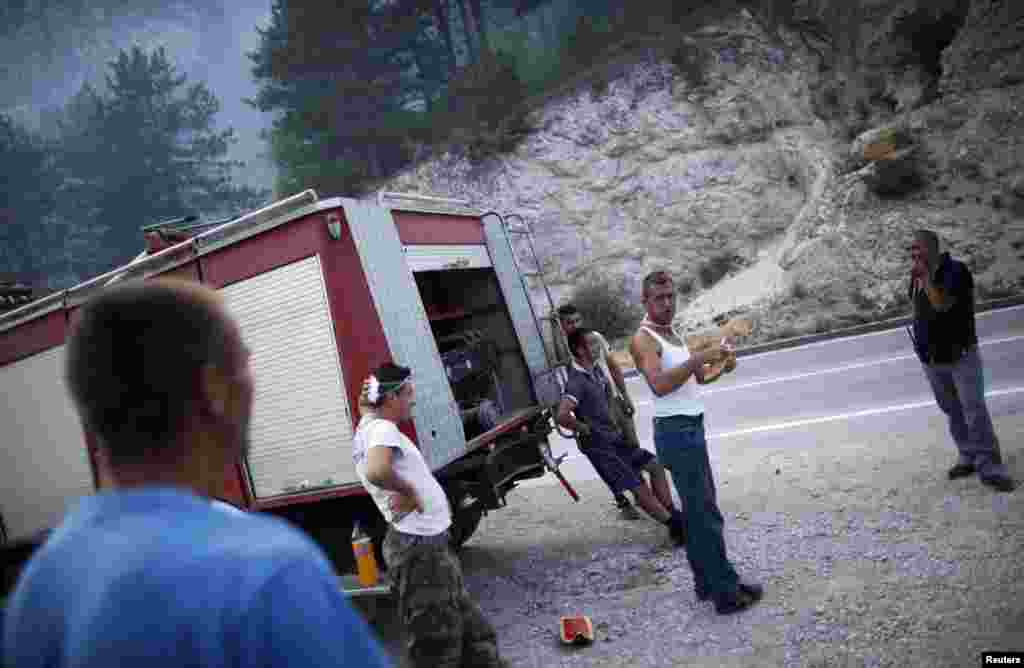 Bosnia and Herzegovina - Firefighters and locals wait for a helicopter to drop water over a forest fire in Jablanica August 6, 2013.