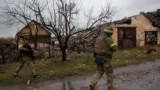 Ukrainian servicemen walk at a street in the frontline town of Lyman