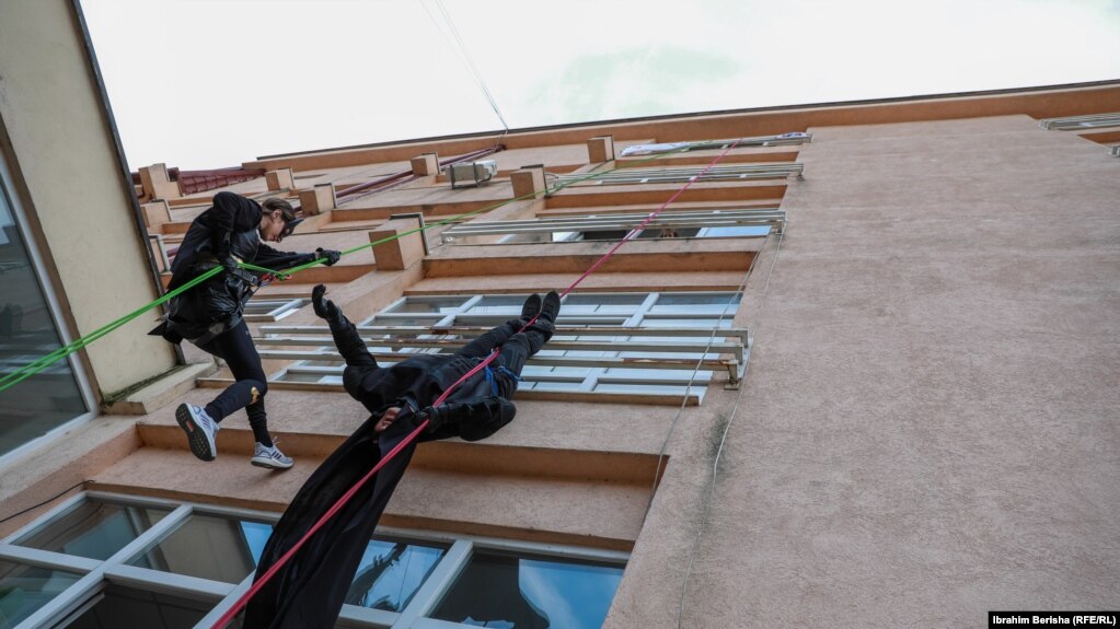 Dy alpinistë të veshur si Batman duke u lëshuar me litarë në Klinikën e Pediatrisë në Prishtinë.