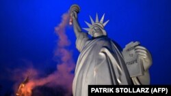 O replică a Statuii Libertății emițând fum, creată de danezul Jens Galschiot 