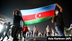 People carry the Azerbaijni national flag as they rally in support of the country's army in Baku on July 14.