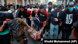 A soldier, badly wounded during clashes with anti-government protesters, is carried by demonstrators to a hospital during the ongoing protests in Baghdad on November 26.