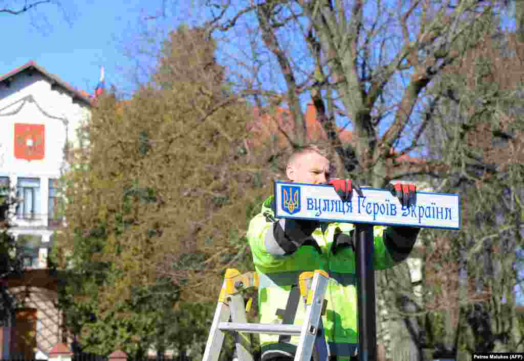 A worker installs a street sign in Ukrainian renaming a road leading to the Russian Embassy (visible in background) in Vilnius, Lithuania, in March 2022. The road is now called Ukrainian Heroes Street.