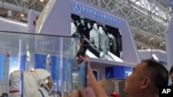 A man takes a photograph of the model of a Chinese astronaut during the 12th China International Aviation and Aerospace Exhibition, also known as Airshow China 2018, in Zhuhai city, south China's Guangdong province, Wednesday, Nov. 7, 2018. (AP Photo/Kin 