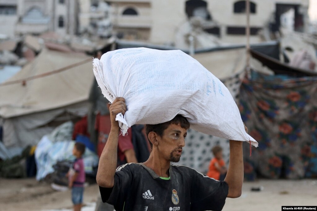 Një burrë palestinez duke bartur mbi kokë një thes me ndihma, më 22 korrik.