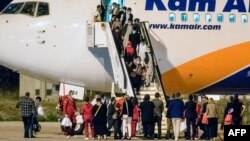 Refugjatët afganë zbresin nga një aeroplan pas mbërritjes në Aeroportin Ndërkombëtar të Shkupit, në Shkup më 30 gusht 2021. 
