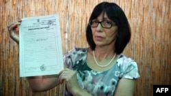 Mirjana Novokmet shows her missing baby's birth certificate in front of her home in Zemun, near Belgrade, in 2013.