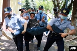 Қазақстан полициясы оппозиция ұйымдастырған митингінің қатысушысын ұстап әкетіп барады. Митинг үкімет карантинді жеңілдеткен күні өтті. Алматы, 6 маусым 2020 жыл.