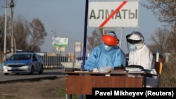 Медики в защитной одежде на въезде в Алматы, закрытый на карантин с 19 марта.