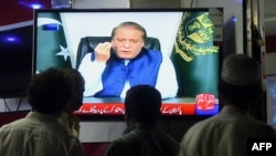 Мужчины смотрят на экран телевизора, по которому транслируют выступление премьер-министра Пакистана Наваза Шарифа в Карачи. 22 апреля 2016 года. 