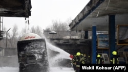 Afghan firefighters work at a site after a building caught fire late last night at a petrol station in Charahi Abdul Haq in Kabul on January 4.