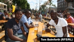 Three Congolese students have a beer in the fan zone in Kyiv. While some longtime residents stay away for fear of violence, visiting fans talk of a welcoming atmosphere.