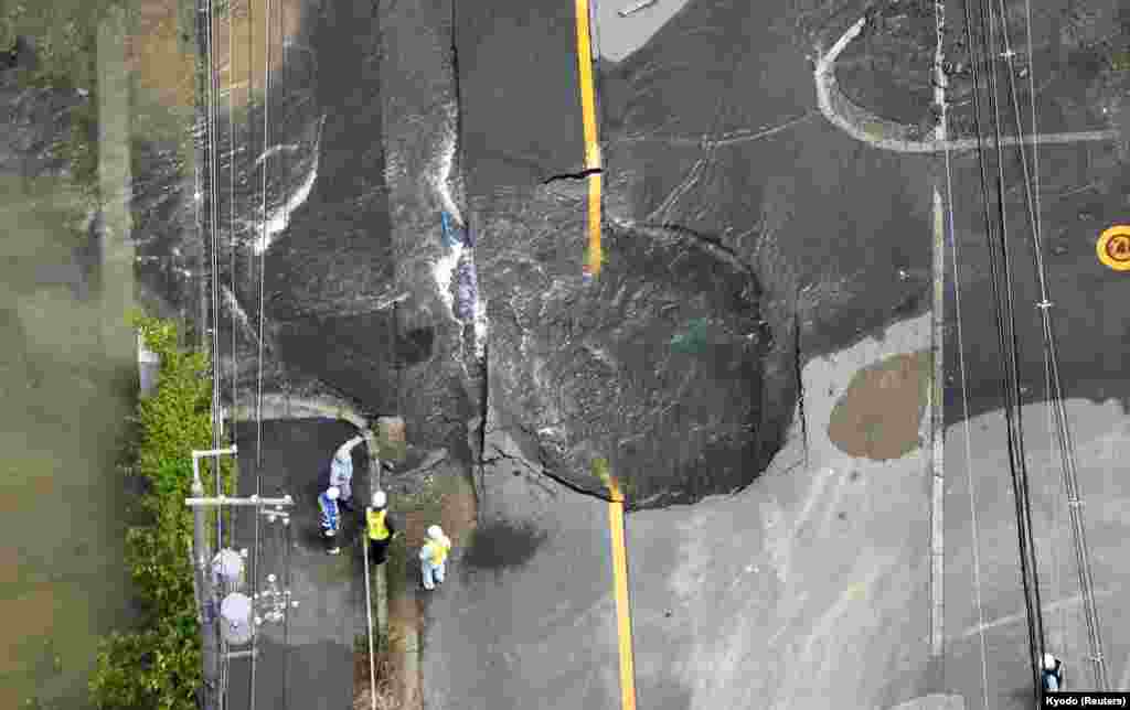 Water flows out from cracks in a road damaged by an earthquake in Takatsuki in western Japan. (Kyodo/via Reuters)