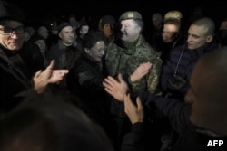 Президент Украины Петр Порошенко (в центре), приветствующий украинских военнослужащих, которые были заключены в плен, после их освобождения во время обмена пленными, 27 декабря 2017 года
