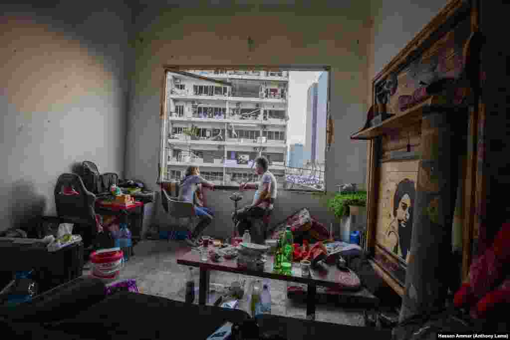 Fouad Armali smokes water-pipe in his destroyed apartment at Gemmayzeh neighborhood, which suffered extensive damage from the Tuesday's explosion at the seaport of Beirut, Lebanon, Thursday, Aug. 6, 2020.