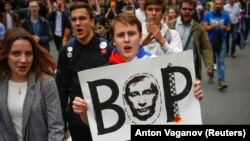 Mladi ruski opozicijski demonstrant nosi sliku predsjednika Vladimira Putina s ispisanom rječju “lopov” na ruskom jeziku, tokom skupa zbog planiranog povećavanja penzijskog staža u Sankt Peterburgu 9. septembra.