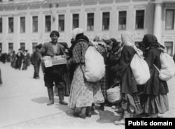 A man holding a religious icon surrounded by peasant women at the Kremlin.