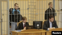 Dzmitry Kanavalau (left) and Ulad Kavalyou are seen in the defendants' cage before court hearings in Minsk on September 15, 2011.