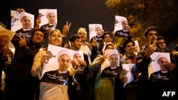 Iranian supporters of Foreign Minister Mohammad Javad Zarif flash the victory sign as he arrives at Tehran's Mehrabad Airport on November 24.