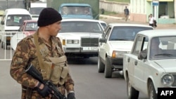 FILE: An officer of special police forces guards a road outside Tashkent