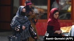 Afgán nők haladnak el egy tálib fegyveres előtt 2021. szeptember 2-án Kabulban
