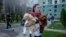 A Ukrainian woman with her dogs leaves the site of a Russian air strike on Kharkiv on July 24. 